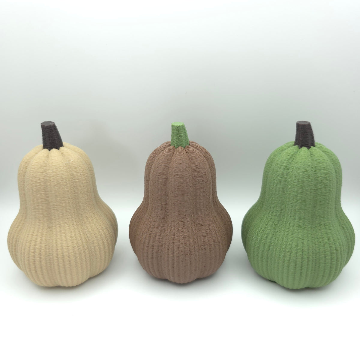Deko-Butterkürbisse in Beige, Braun und Grün vor hellem Hintergrund.