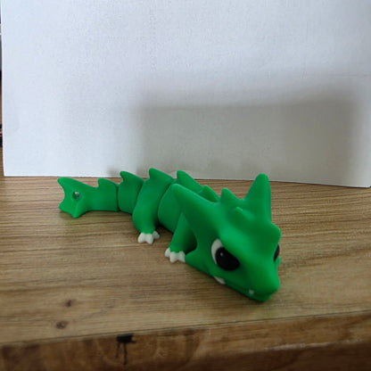 Grüne Neobite-Figur auf einer Holzfläche.